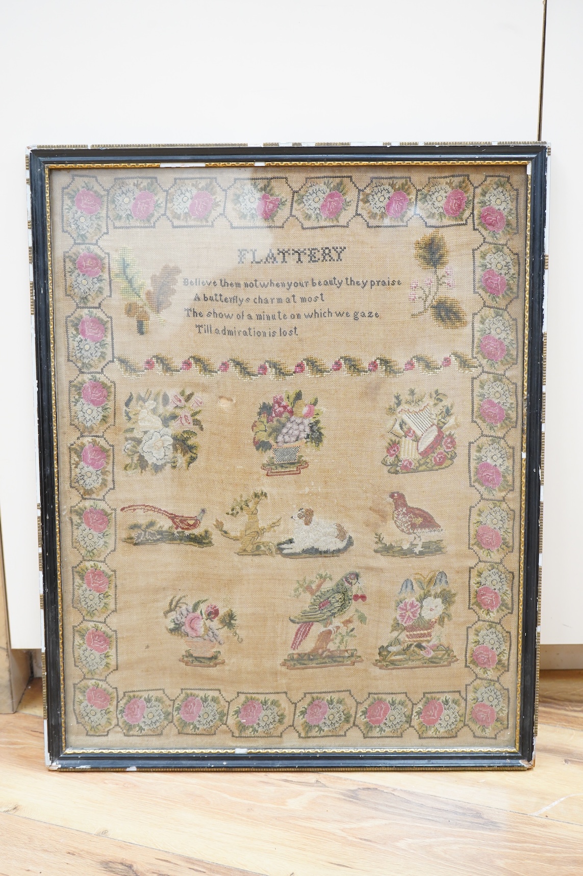 A 19th century finely embroidered sampler. FLATTERY the title to the verse beneath, then below motifs of birds, flowers and a dog, within a wide rose and floral border, 41cm x 51cm. Condition - some staining to backgroun